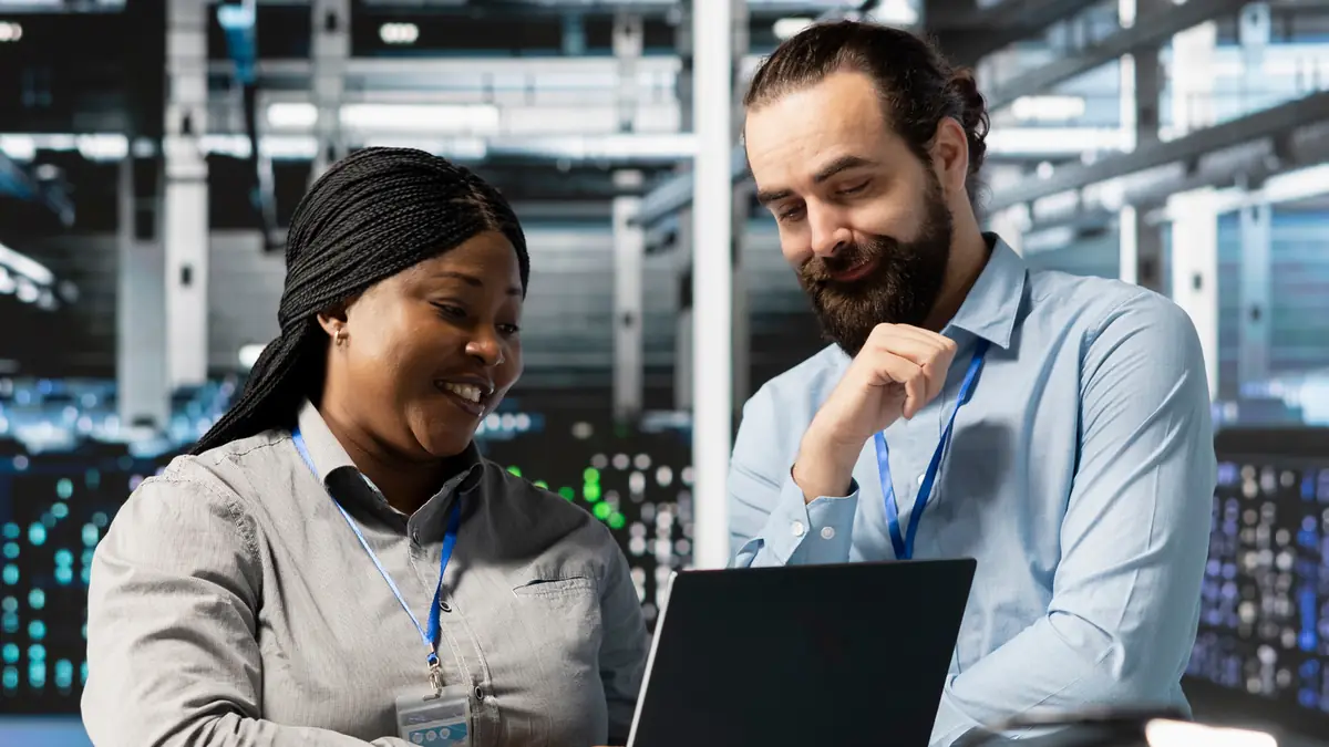 Two IT professionals smiling at a laptop, illustrating real-world results of PSTN calling through Operator Connect Express.