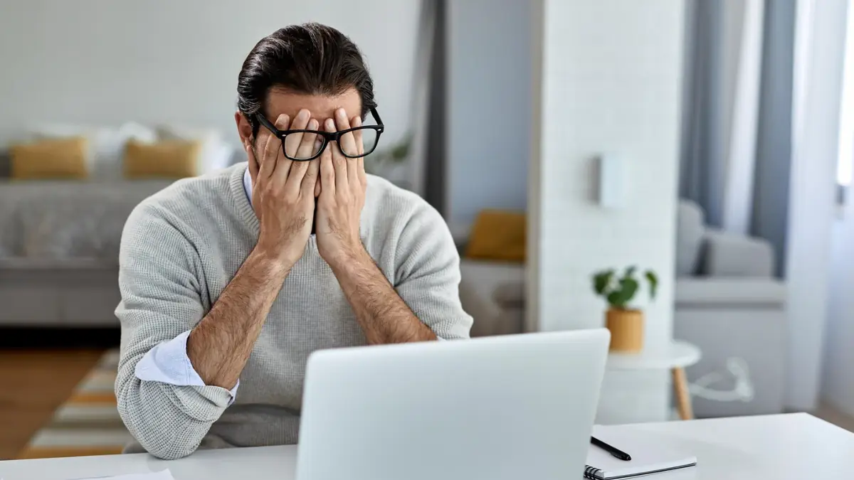 Man sitting at laptop with hands on face, frustrated by traditional PSTN setup complexity in the Microsoft Teams Ecosystem.